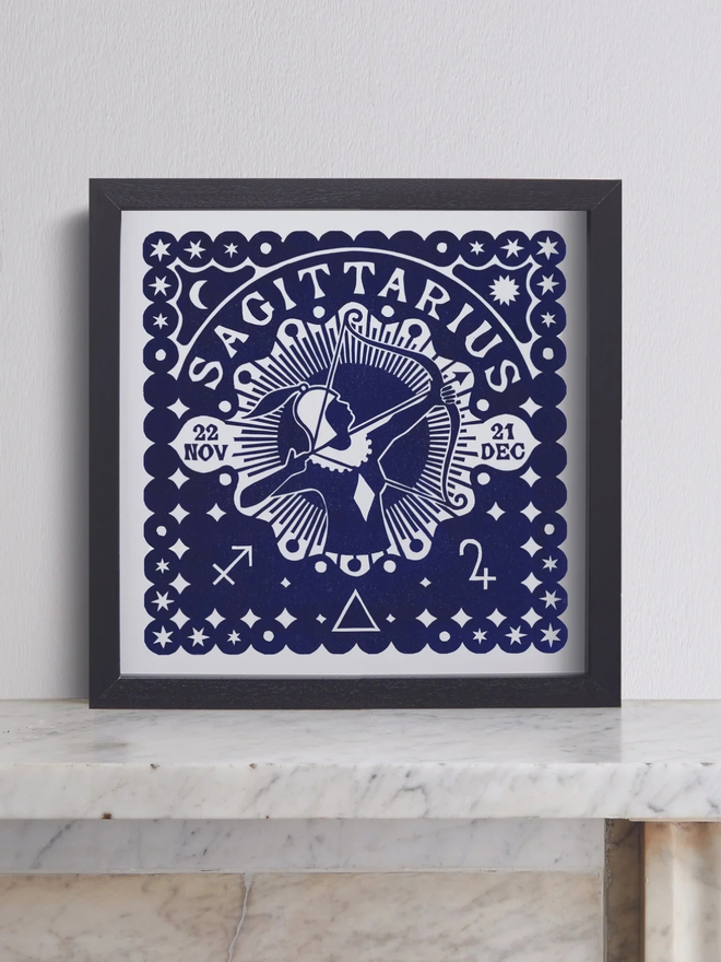 saggitarius zodiac linocut. a linocut archer and zodiac symbols printed on a blue background.