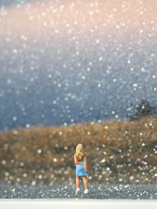 TIny figure of a young woman looking out from a hill overlooking the beautiful sunset through clouds (close up)