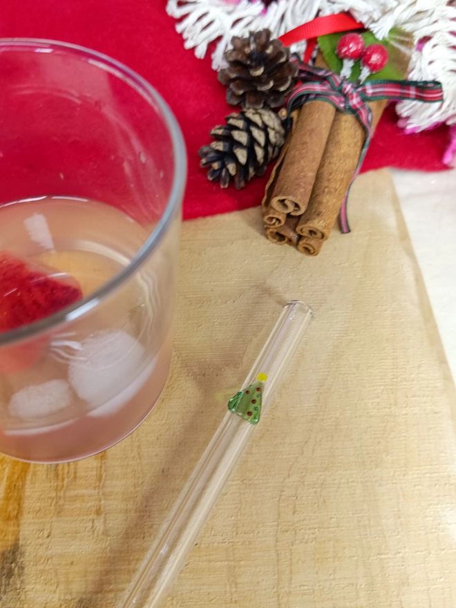 Christmas tree straw lain next to a glass with chrsitmassy background