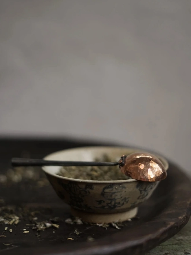 Copper And Stainless Steel Scoop, a metal scoop sitting on a bowl of herbs. 