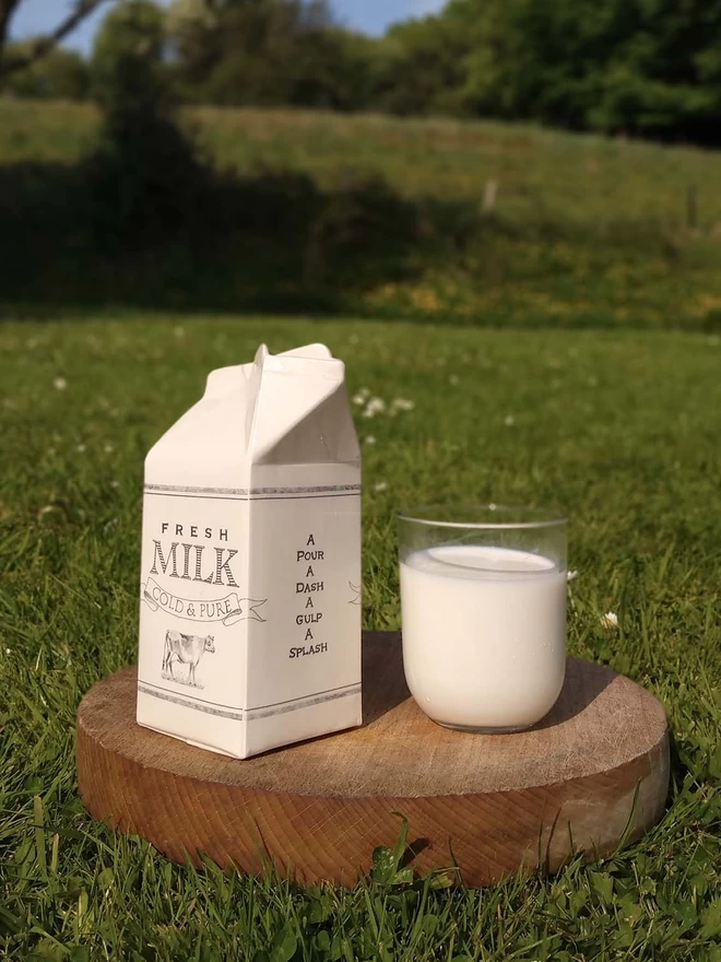 A handmade ceramic milk carton with a fresh glass of milk.