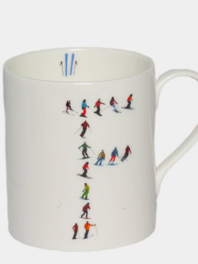 A simple white mug illustrated with an ‘F’ made of small, multicoloured skiers. The mug is set against a plain, white background.