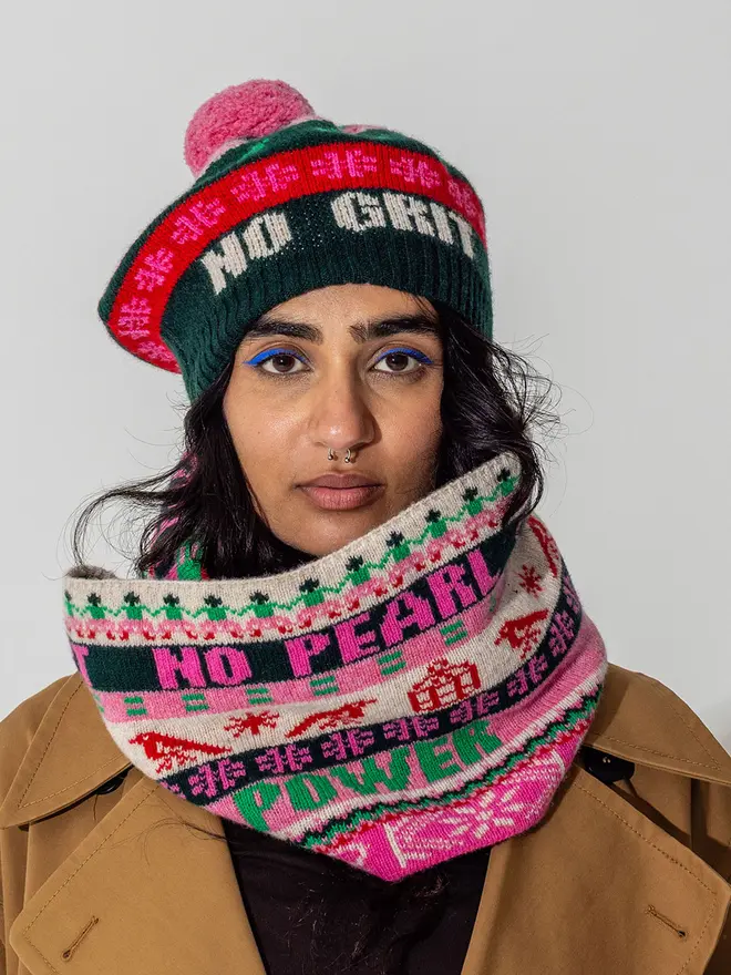 Model wearing the fairisle feminist beret in Forest green and bubblegum  featuring the wording No Grit No Pearl
