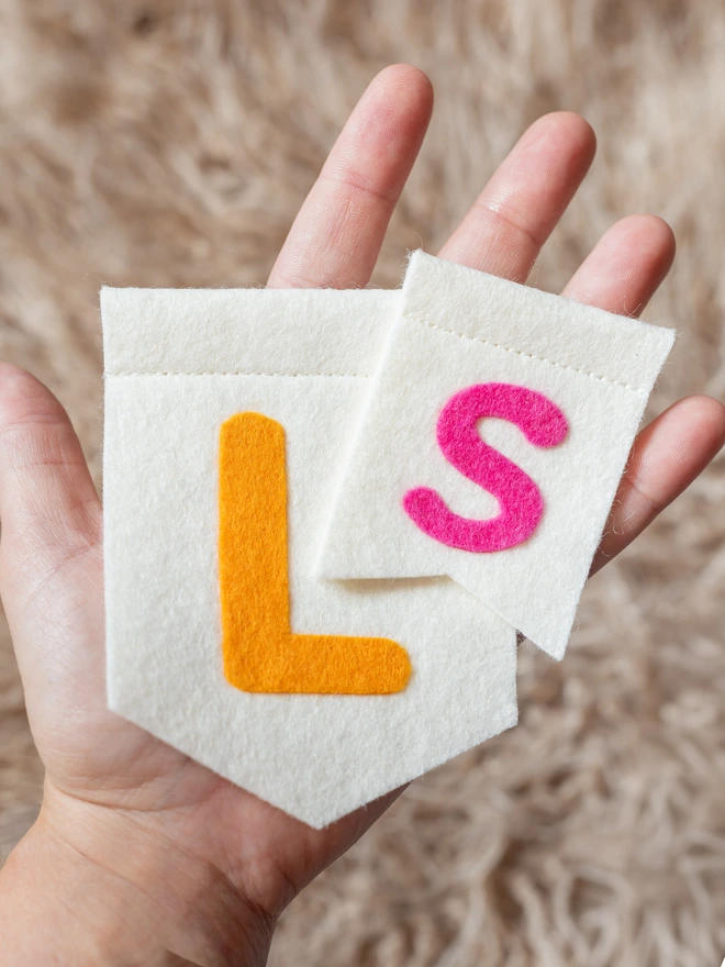 a hand holding 2 felt flags, showing the size difference between small and large.