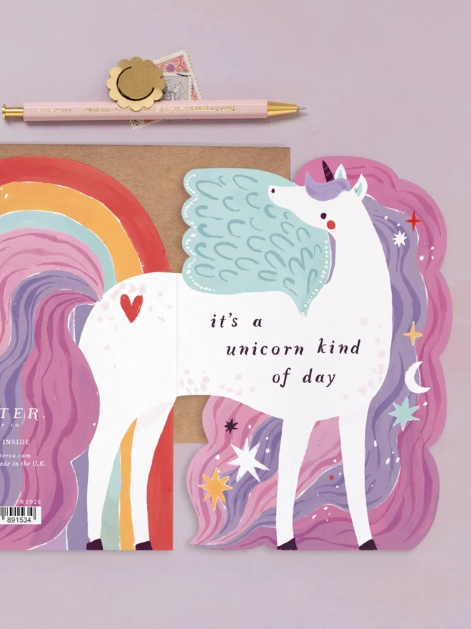 Unicorn Birthday Card beside a rainbow card, with a kraft envelope and a pen