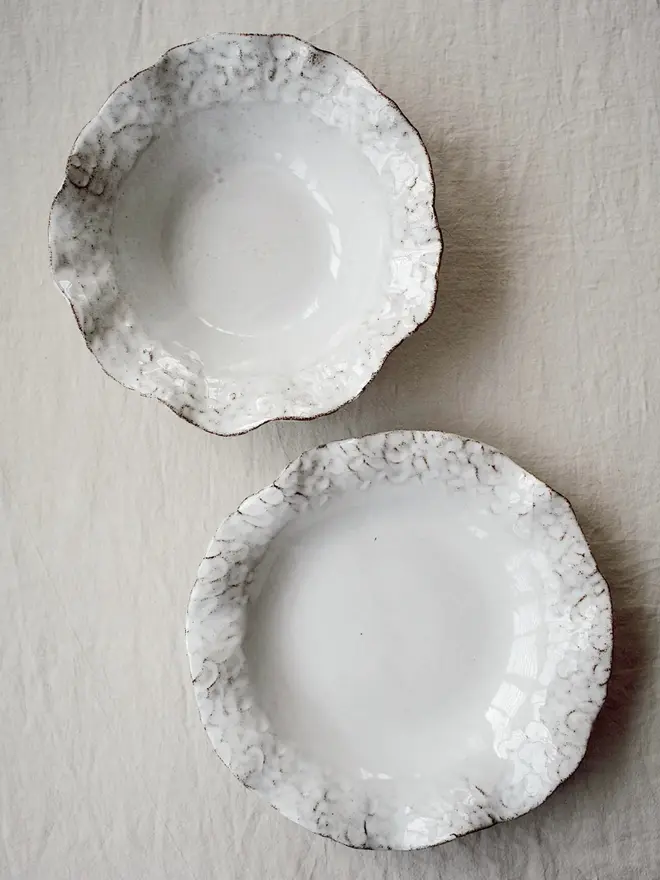 Dapple Stoneware Cereal & Salad Bowl, positioned with another ceramic, placed on a table cloth. 