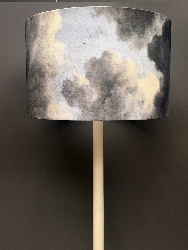 An original design lampshade made with  an exclusive cloud fabric, against a dark grey wall