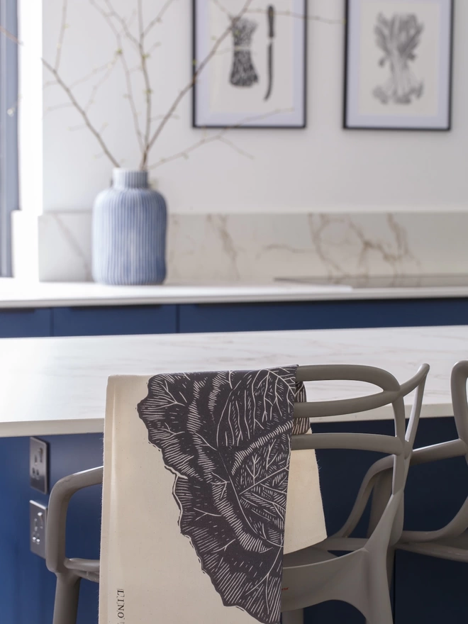 Picture of a tea towel in a kitchen with an image of a savoy cabbage, taken from an original lino print