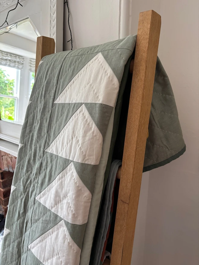 Flow Light Sage Green Linen Quilt. A green single quilt with geometric white triangle design.