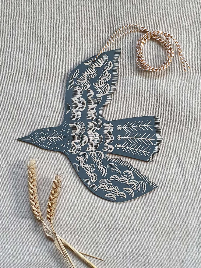 Hanging wooden hand printed bird decoration in a teal colour.