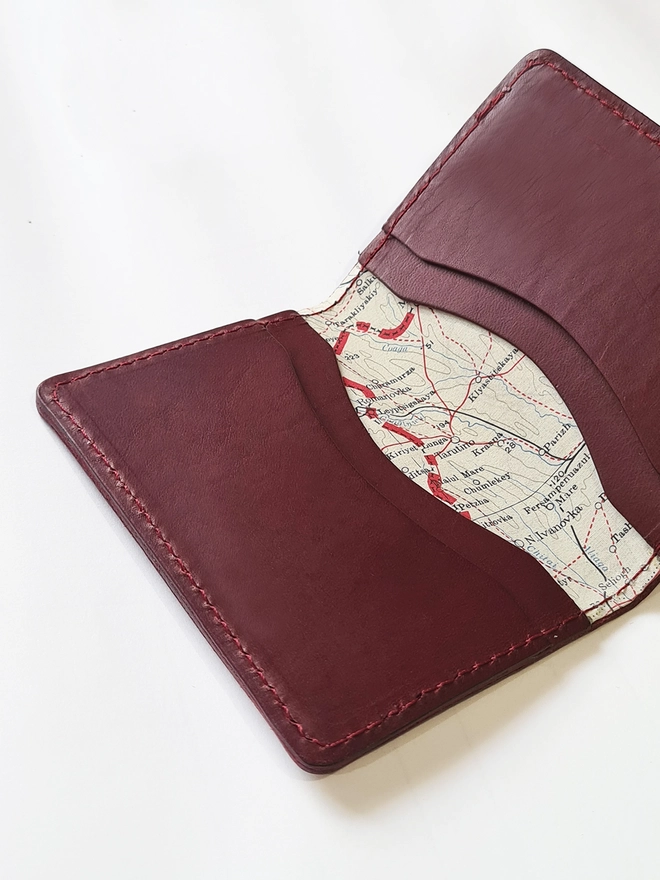 a red vegetable tanned leather wallet lined with a silk map from the Cold War by Natthakur