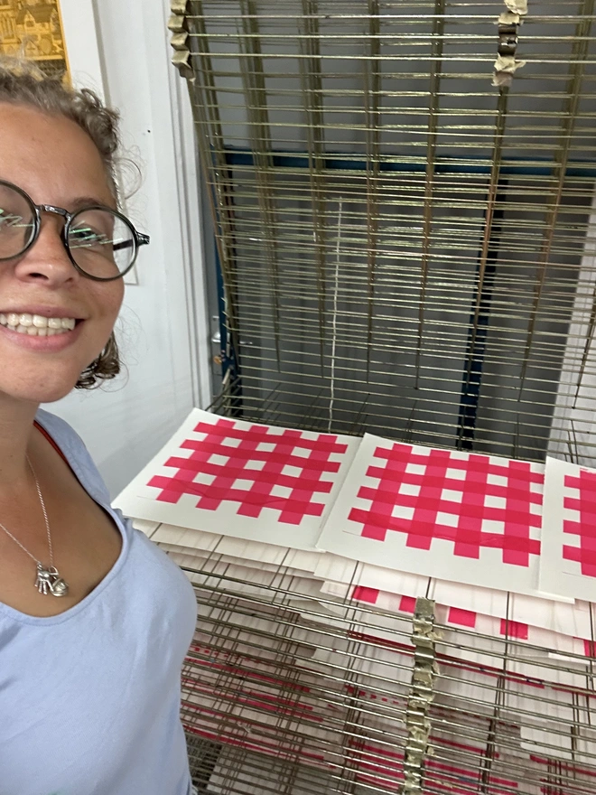 Emily with a drying rack of hand screen printed papers 