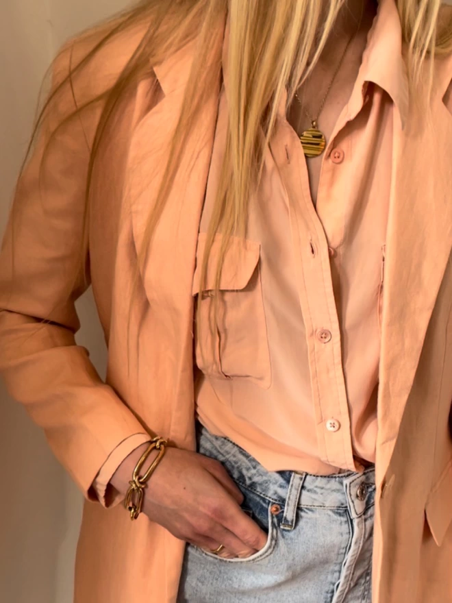 stunning golden atlas coin pendant necklace worn back with peach silk