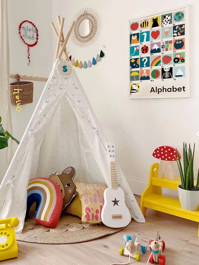 illustrated alphabet wall print on white wall with a childs teepee tent and toys