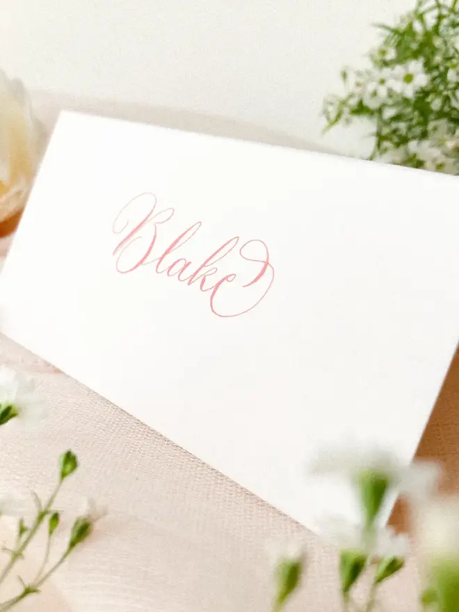 personalised calligraphy place cards. white place card with name in calligraphy pink ink.