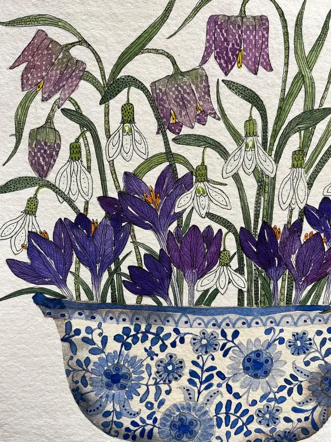 crocus, snowdrops and fritillary flowers in a blue and white, patterned ceramic vessel