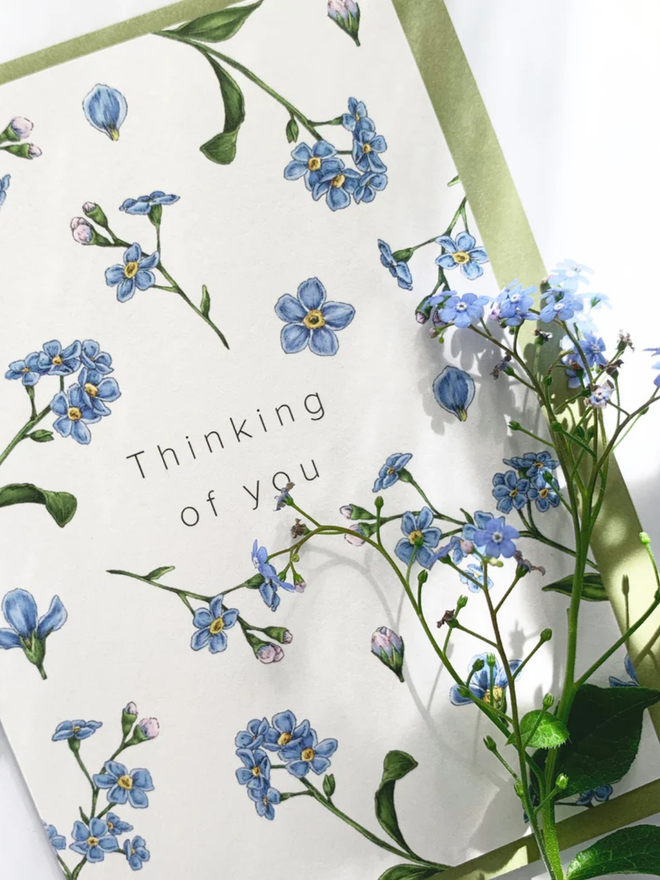 'thinking of you' illustrated champ de fleur card. a white floral card photographed against a white background.