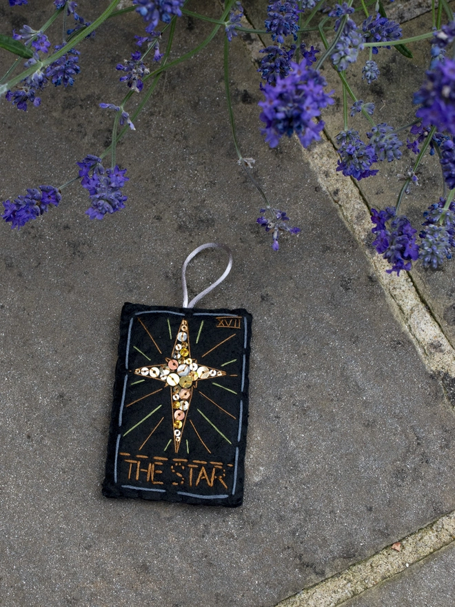 A handcrafted felt ornament with sequins and embroidery depicting "The Star" tarot card. 