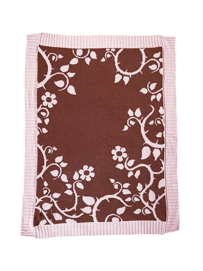 Product shot of the reverse colourway of the briar rose baby blanket, chocolate brown background with a blush pink trailing design of flowers and thorns.