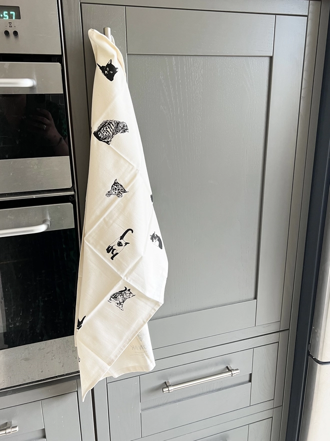 Pussycats tea towel hung up on the cupboard handle by it hanging loop