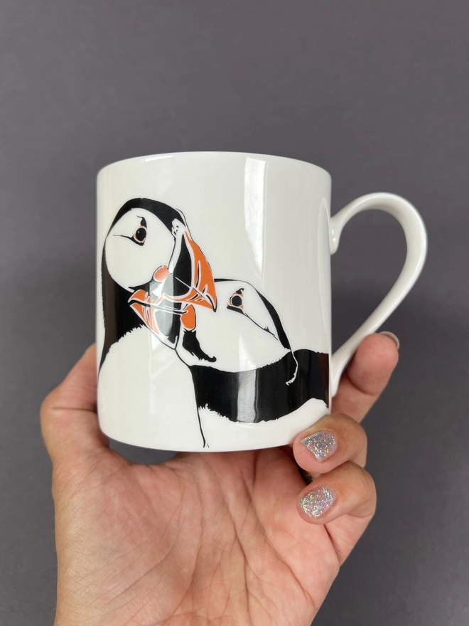 Close up of the front of the 'puffin nuzzle' mug showing two puffins lovingly nuzzling into each other, perfect for a wedding or anniversary present as puffins mate for life