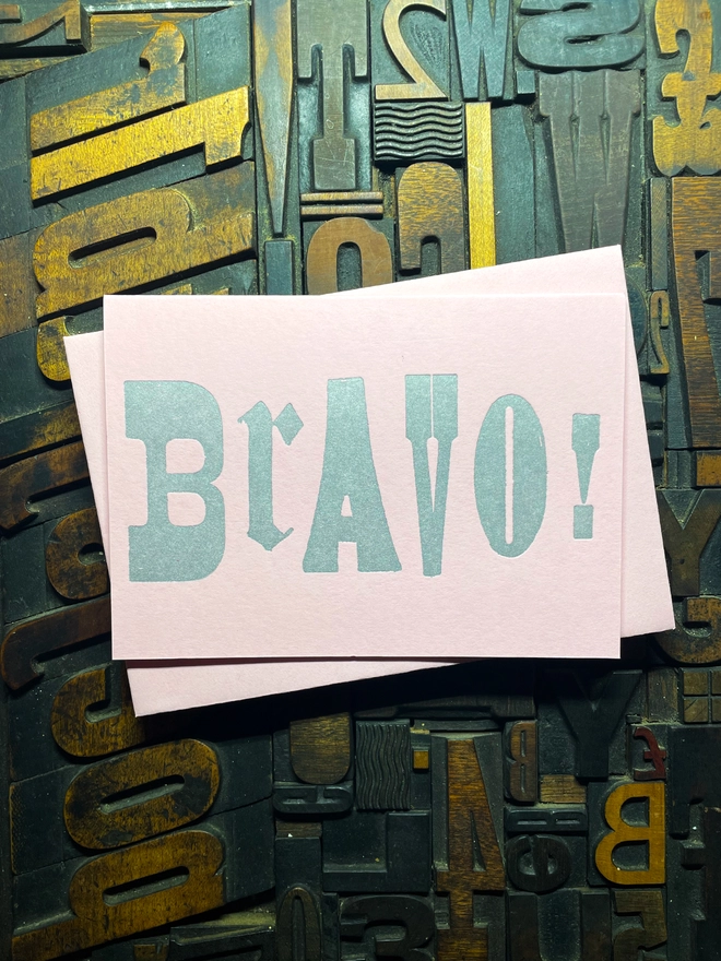 A congratulatory letterpress candy pink card featuring the deep impression word "BRAVO!"; in bold metallic gold letters with a set of colourful envelopes. Perfect for exam results and graduations and other celebrations and milestones.