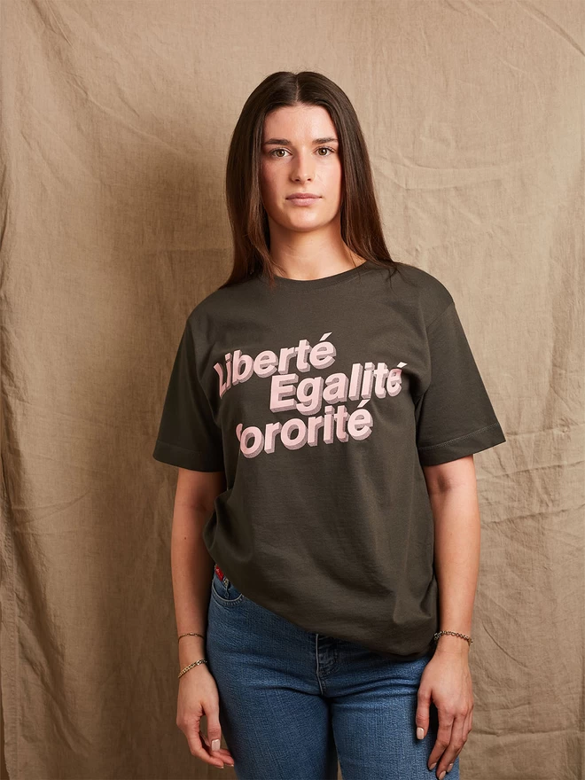 Model is wearing a charcoal grey cotton t-shirt with the slogan Liberté, Egalité, Sororité in pale pink written on the front