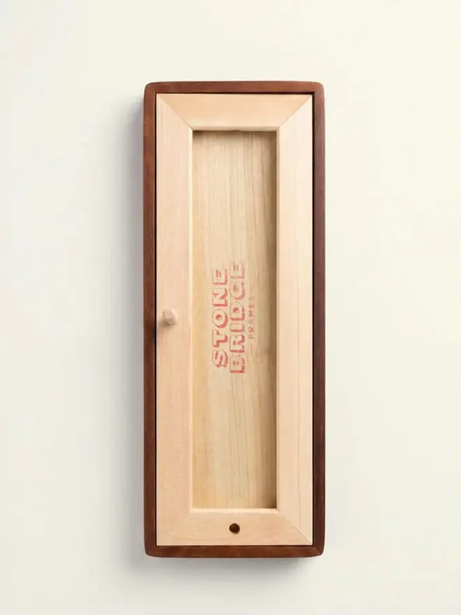 Back of the Mounted Photobooth Solid Wood Frame, with red background, hanging on a white wall. 