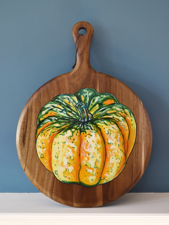 Wooden serving board with a handpainted design of a carnival squash