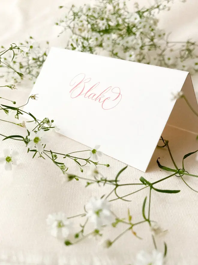 personalised calligraphy place cards. white place card with name in calligraphy pink ink.