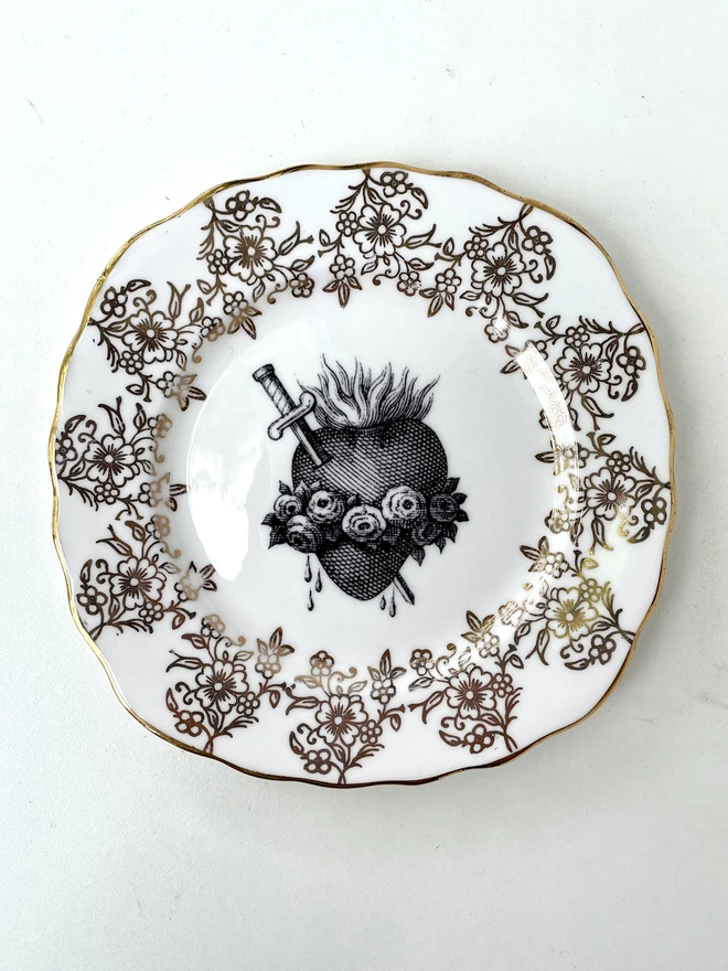 a vintage plate with an ornate gold border and in the centre is an old illustration of a beautiful sacred heart