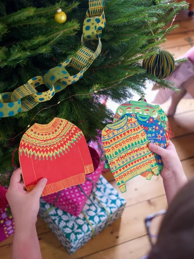 Christmas Jumpers Garland held in front of a Christmas tree