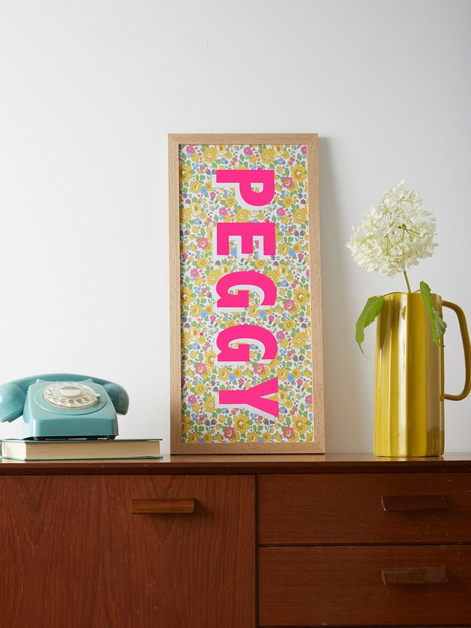 Personalised framed word/name picture in neon pink with white highlights on Liberty Betsy yellow fabric