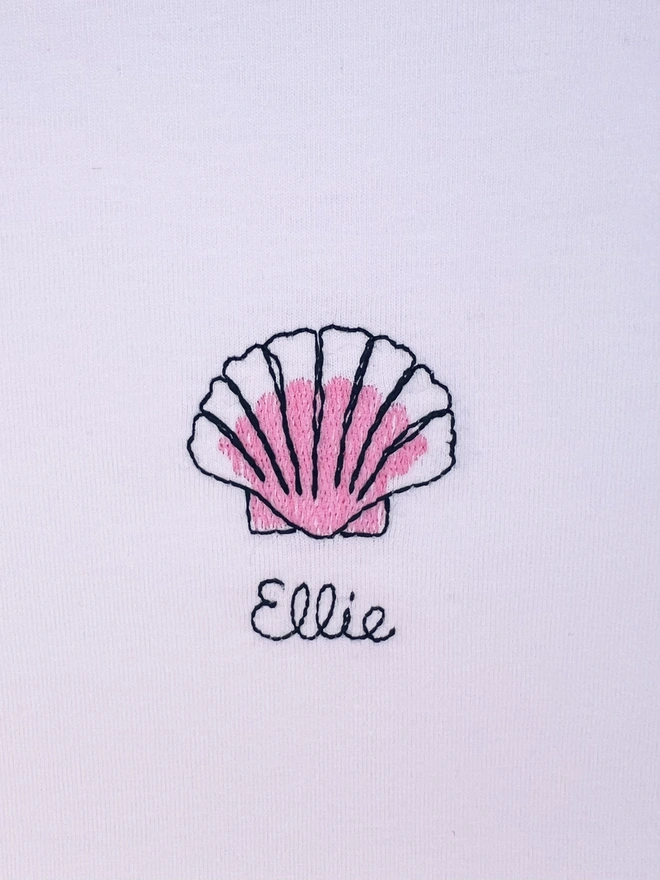     White T-shirt embroidered with pink shell motif and the name “Ellie”