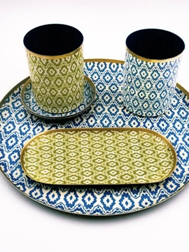 Large Enamel Circular Tray. A coordinating set of blue and lime green ikat-patterned homeware, including two pots with gold rims, an oval tray and a small dish on a large round tray. The matching geometric designs make a stylish collection for desk, dressing table or bathroom storage.