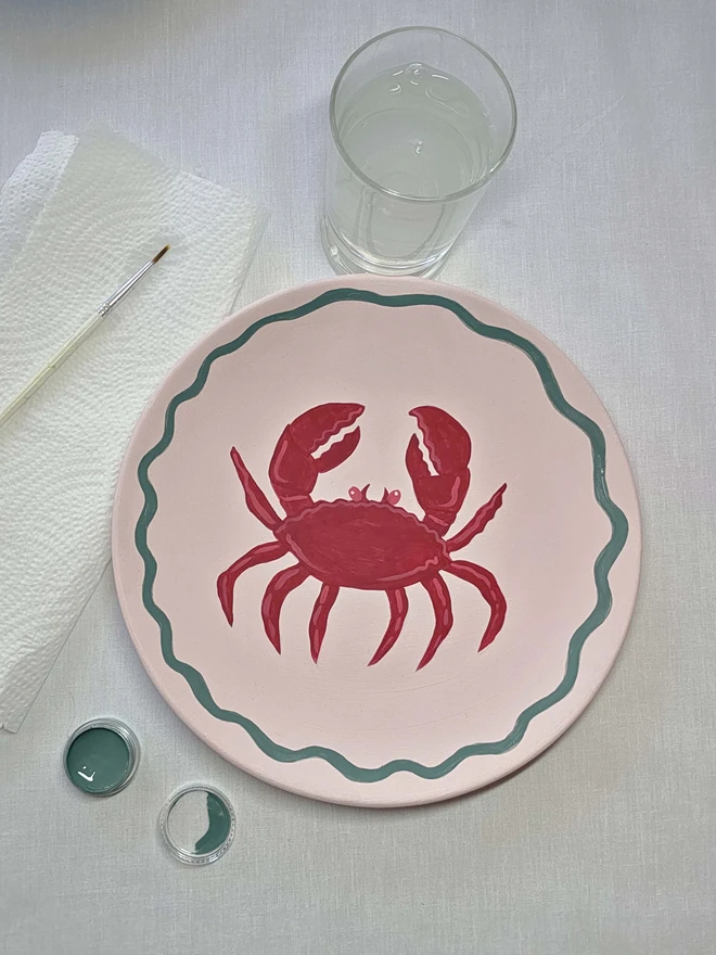 Pale pink ceramic plate with crab design painted on it 