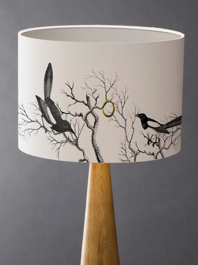 Handmade lampshade featuring cheeky magpies with gleaming gold details, inspired by traditional folklore and whimsical home decor.