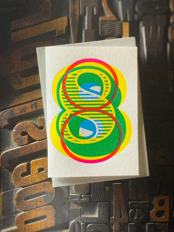 Handmade letterpress 8th birthday card featuring bold overlapping numerals printed in vibrant fluorescent cyan, magenta and yellow inks. Each card is individually hand printed using traditional letterpress techniques on luxury paper stock, creating a beautifully tactile finish with a deep impression and rich layered colours inspired by the CMYK printing process. Printed on a traditional letterpress from 1915. A wonderful artisan printed birthday card.