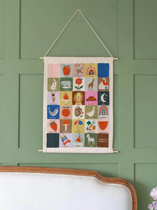 Colourful Rainbow Alphabet Fabric Banner, hanging on a green wall. 