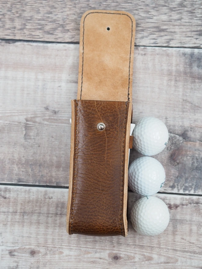 Handmade leather golf ball and tee holder accessory. A tall slim leather case designed to carry 3 golf balls and 2 tees.