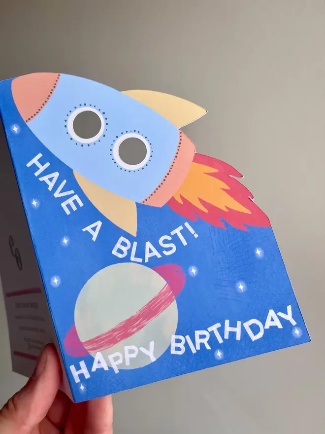 have a blast rocket birthday card. blue card with illustrated rocket and planets.