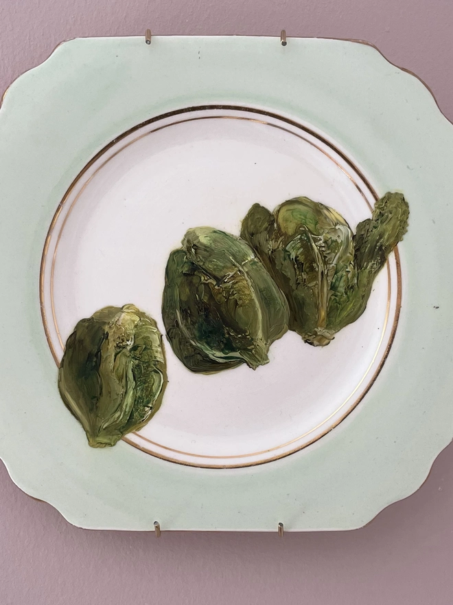three brussels sprouts painted on vintage plate