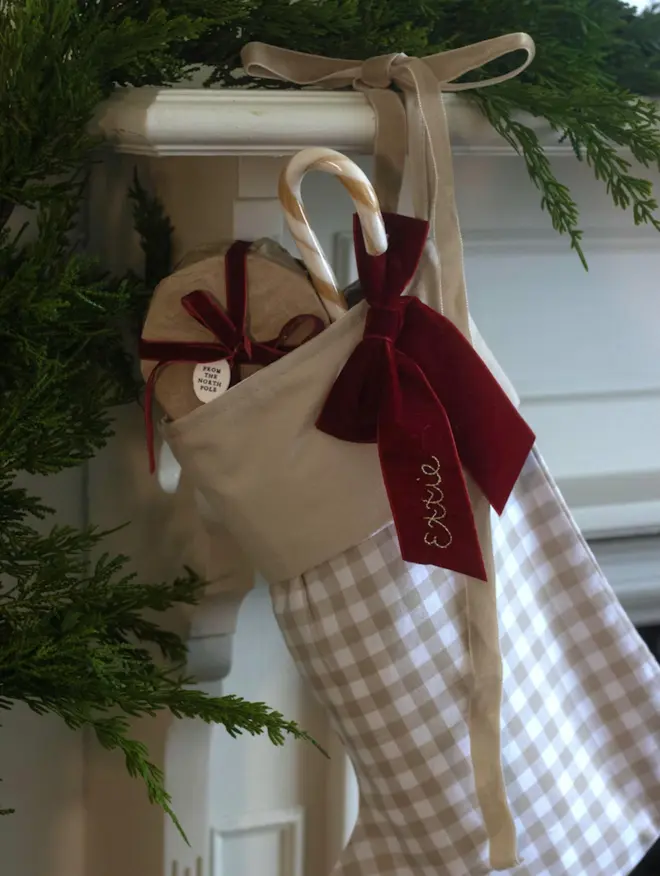 beige gingham stocking with dark red velvet bow, embroidered with a name