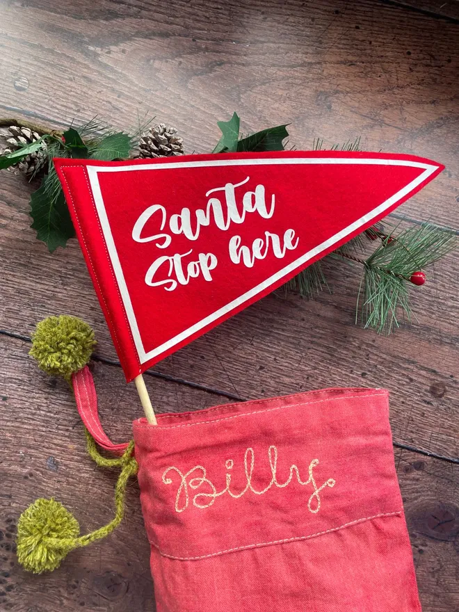 Santa stop here mini pennant flag poking out the top of a christmas stocking