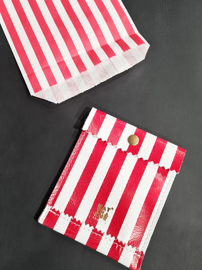 leather red and white striped mini coin purse packaged in a red and white striped paperbag