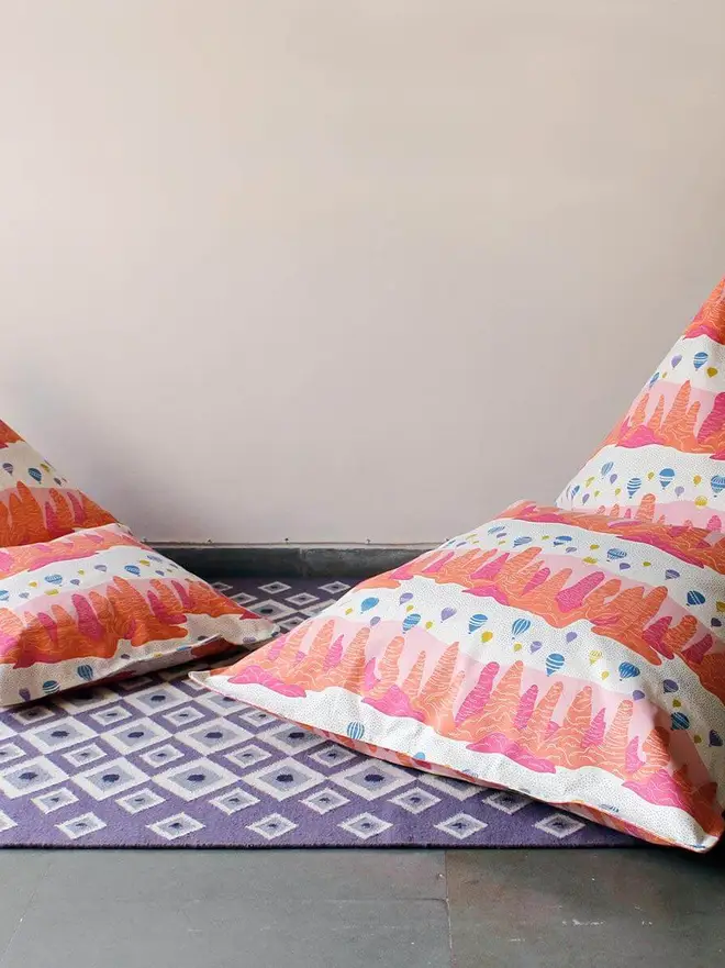 Fairy Chimney Bean Bag Cover, a coral bean bag sitting on a decorated floor. 
