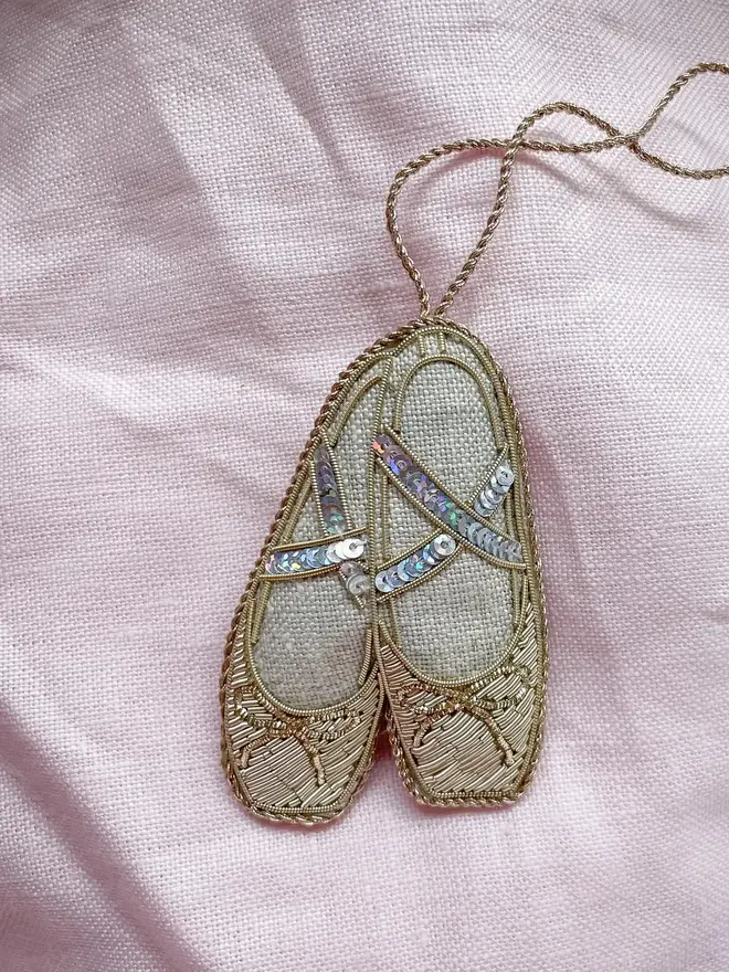 embroidered linen ballet slippers decoration. ballet slippers decoration photographed on pink fabric background.