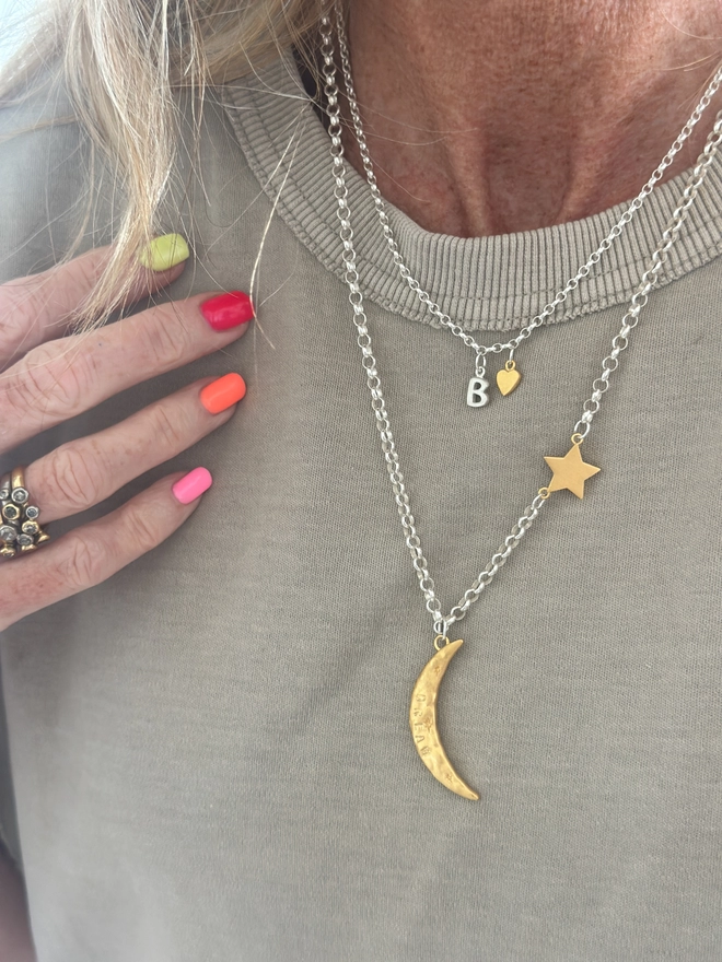 model wears a textured gold moon charm sits on a sterling silver heavy belcher chain, with linked gold cosmo star charm