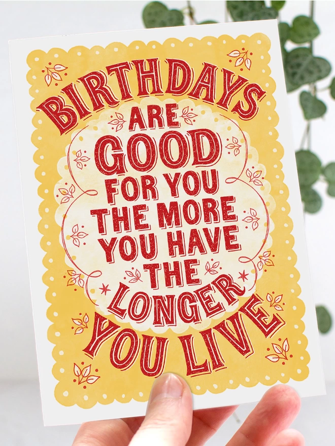 hand holding red and yellow hand lettered birthdays are good for you card