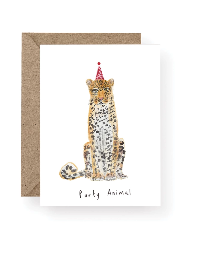 Leopard Birthday Card, Cards features a Sitting Leopard Wearing A Party Hat And Has Been Handpainted In Watercolour.  There is Black Handwritten Text Under the Illustration Which Reads Party Animal.  The Card is Shown Sitting On A Brown Kraft Envelope
